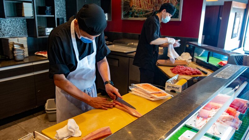 Two chefs preparing sushi.